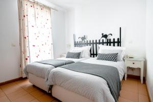 two beds in a bedroom with white walls at Betica Hotel Rural in Pias