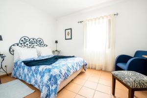 a bedroom with a bed and a blue chair at Betica Hotel Rural in Pias