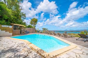 una piscina con sillas y vistas al agua en Ty Paradis Magnifique Lodge pour un couple en Sainte-Anne
