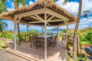 a wooden gazebo with a table and chairs at Ty Paradis Magnifique Lodge pour un couple in Sainte-Anne