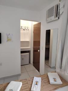 - une salle de bains avec 2 serviettes sur un lit et un miroir dans l'établissement Jequitiba Hotel Frente ao Mar, à Guarujá