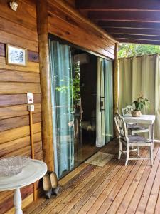 eine Holzterrasse mit einem Tisch und Stühlen darauf in der Unterkunft Chalés Paris in Paraty