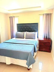 ein Schlafzimmer mit einem blauen Bett, einer Kommode und einem Fenster in der Unterkunft Bay Front Apt 208 in Portmore