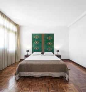 a bedroom with a large bed with a green headboard at Hotel Tivoli Beira in Beira