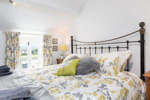 a bedroom with a bed with yellow and gray pillows at Red Robin Cottage in Gaerwen