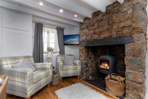 una sala de estar con 2 sofás y una chimenea de piedra. en Red Robin Cottage en Gaerwen