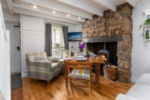 a living room with a table and a stone fireplace at Red Robin Cottage in Gaerwen