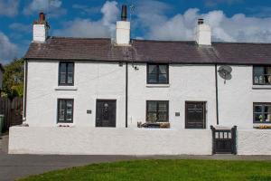 a white house with a bench in front of it at Red Robin Cottage in Gaerwen