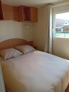 1 dormitorio con cama blanca y ventana en LA CASA, en Biville-sur-Mer