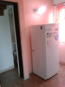 コロンにあるDepartamento Costa del Uruguayのピンクの壁の客室で、白い冷蔵庫が備わります。