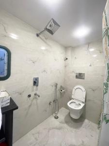 a white bathroom with a toilet and a shower at Kashi Dham Home Stay in Varanasi