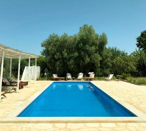 a blue swimming pool with chairs and a tent at I Trulli Di Acquarossa in Cisternino