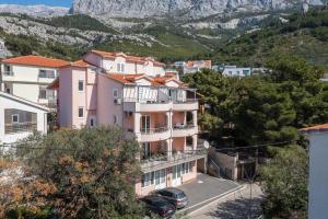 a pink building with a car parked in front of it at Apartments Luka Toni in Krvavica