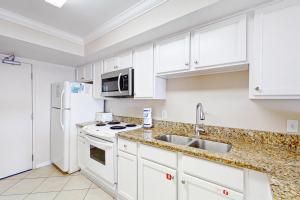 a kitchen with white cabinets and a white refrigerator at Ocean House II 2602 in Gulf Shores