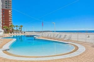 a swimming pool with chairs and the ocean in the background at Ocean House II 2602 in Gulf Shores