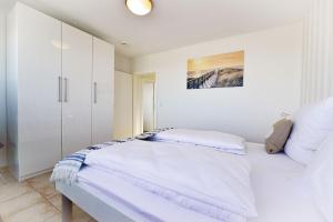 ein weißes Schlafzimmer mit einem Bett und einem Schrank in der Unterkunft Haus am Waldbad AW15 in Cuxhaven