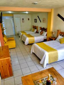 a hotel room with three beds and a table at Hotel Carnaval in Huejotzingo