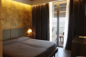 een slaapkamer met een bed en een raam met een balkon bij Hotel Aurora in Sirmione
