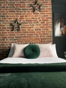 ein grünes Kissen auf einem Bett vor einer Ziegelwand in der Unterkunft Salt Life One Bedroom Apartment in Brighton & Hove