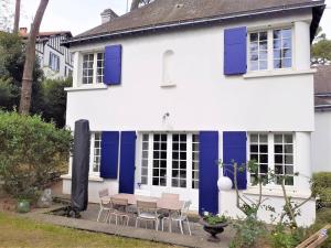 a white house with blue shutters and a table and chairs at Maison La Baule, 6 pièces, 8 personnes - FR-1-392-174 in La Baule