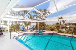 a swimming pool with two chairs and an umbrella at Life at the Canal in Cape Coral