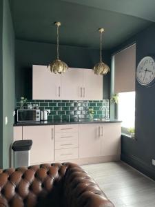 a kitchen with white cabinets and a clock on the wall at Salt Life One Bedroom Apartment in Brighton & Hove