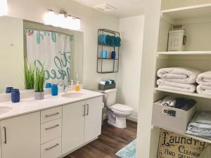 ein Badezimmer mit einem Waschbecken, einem WC und einem Spiegel in der Unterkunft A Perfect Getaway in the Heart of the Action in Las Vegas