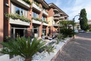 a building with plants in front of a street at Hotel Aurora in Sirmione