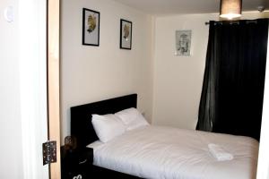 a bedroom with a bed with white sheets at Glamorous Two bed room flat in London