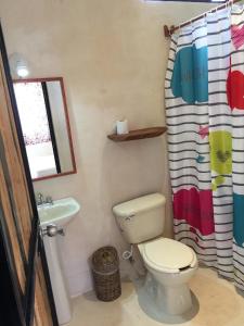 a bathroom with a toilet and a sink and a shower curtain at Aldea Jaguar in Francisco Uh May