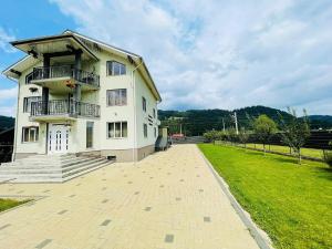 a large white building with a balcony and a grass field at Sweet Home Bucovina- Baza perfecta pentru explorarea Bucovinei in Frasin