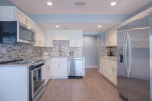 a kitchen with white cabinets and a stainless steel refrigerator at Shore To Please Beach Oceanfront Patio Pet Friendly in Jacksonville Beach