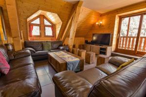 sala de estar con sofás de cuero y TV de pantalla plana en Chalet LEPERVIERE, en Vaujany