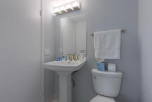 a white bathroom with a toilet and a sink at A Wave From It All Oceanview 2nd Level Patio in Jacksonville Beach
