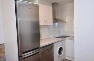 uma cozinha com um frigorífico de aço inoxidável e uma máquina de lavar louça em Apartamento La Barrosa em Chiclana de la Frontera