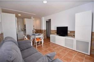uma sala de estar com um sofá, uma televisão e uma mesa em Apartamento La Barrosa em Chiclana de la Frontera