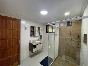 ein Bad mit einer Glasdusche und einem Waschbecken in der Unterkunft Confortável Chalet na Serra proximo ao Centro in Nova Friburgo