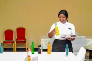 a woman standing at a table holding a plate with a drink at Mutheto Lodge in Lilongwe