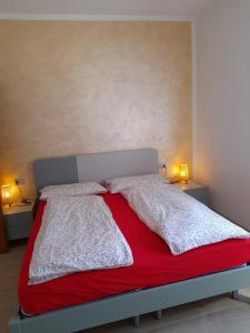 ティニャーレにあるCasa Giulia sul Gardaのベッドルーム1室(赤毛布、ランプ2つ付)