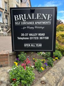 a sign for a store with flowers in a garden at Brialene Holiday Flats in Scarborough