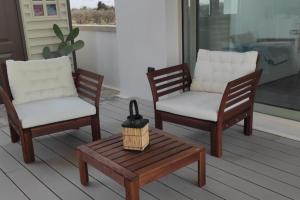 2 Stühle und ein Couchtisch auf einer Veranda in der Unterkunft Loft Salento Sweet Life - con terrazza esclusiva in Vignacastrisi