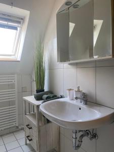 ein weißes Badezimmer mit einem Waschbecken und einem Spiegel in der Unterkunft Ferienwohnung Lütetsburg in Lütetsburg
