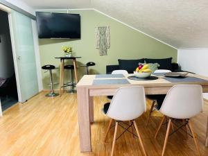 uma sala de estar com uma mesa e cadeiras brancas em Apartment Buga Bilje em Bilje