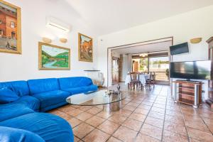 a living room with a blue couch and a flat screen tv at Villa Rita in Racale