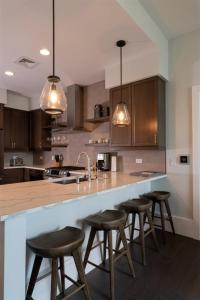 a kitchen with four bar stools at a counter at 'The Views Over Pack Square Park' A Luxury Downtown Condo with Mountain and City Views at Arras Vacation Rentals in Asheville