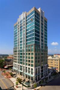 a tall building with glass windows in a city at 'The Views Over Pack Square Park' A Luxury Downtown Condo with Mountain and City Views at Arras Vacation Rentals in Asheville