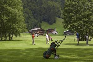 um grupo de pessoas jogando golfe em um campo em Chalet-Hôtel Les Fermes de Pierre & Anna em Le Grand-Bornand