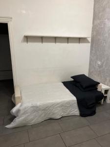 uma cama num quarto com uma parede branca em San Lorenzo Apartment em Roma