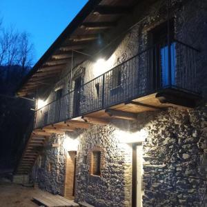 un edificio de piedra con un balcón con luces. en Country House Le Gaie Allegre, en Villar San Costanzo