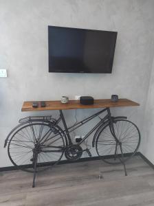 a bike sitting under a table with a television on it at Apparts'hôtel la ferme du gros noyer in Malaucène